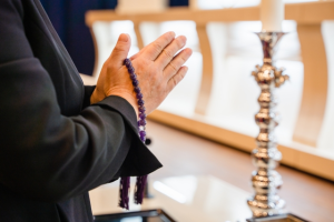 葬儀の白木祭壇の前で合掌する様子